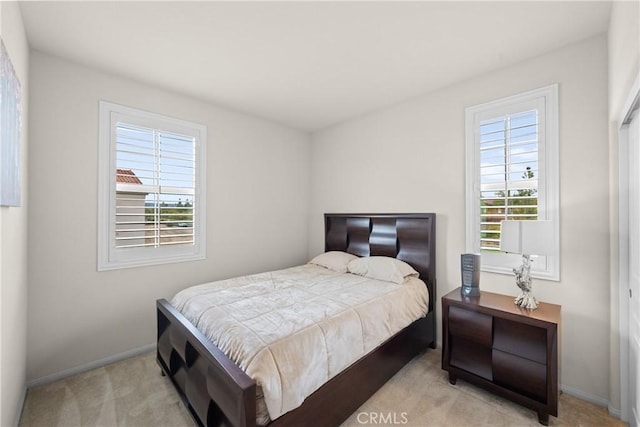 carpeted bedroom featuring baseboards and multiple windows