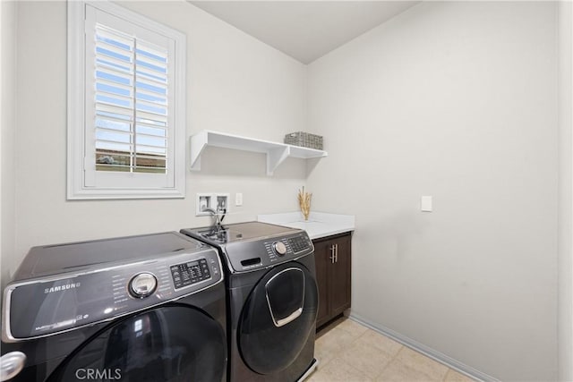 clothes washing area with cabinet space, baseboards, and washer and clothes dryer