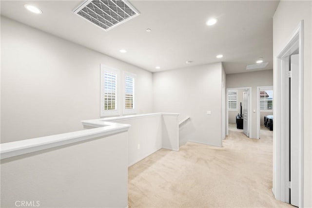 corridor featuring visible vents, recessed lighting, plenty of natural light, and light carpet