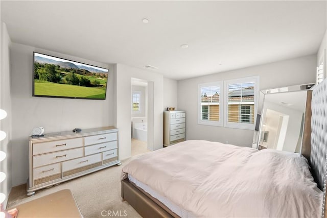 bedroom featuring light colored carpet, ensuite bath, and visible vents