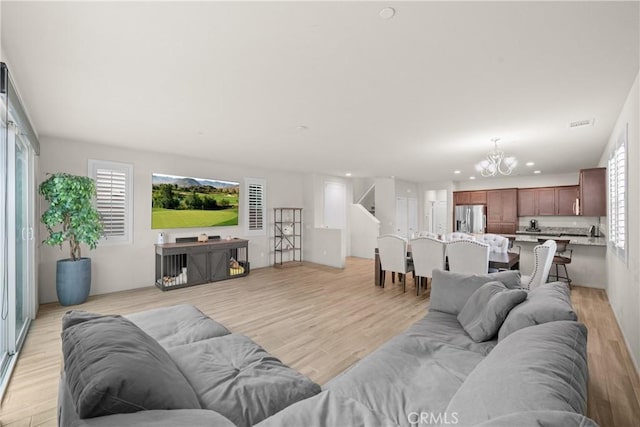 living area featuring light wood-type flooring, recessed lighting, plenty of natural light, and a chandelier