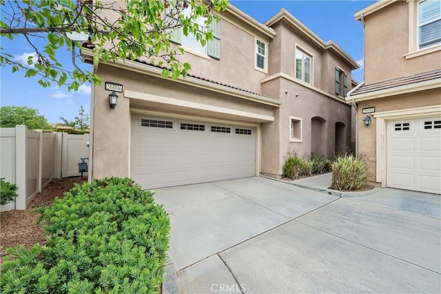 view of front of property featuring fence, stucco siding, driveway, and a garage