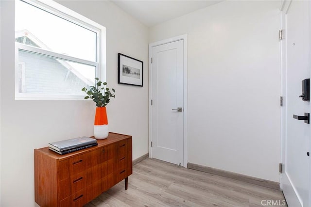 doorway to outside featuring baseboards and light wood finished floors