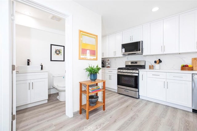 kitchen with a sink, light countertops, stainless steel appliances, and light wood-style flooring