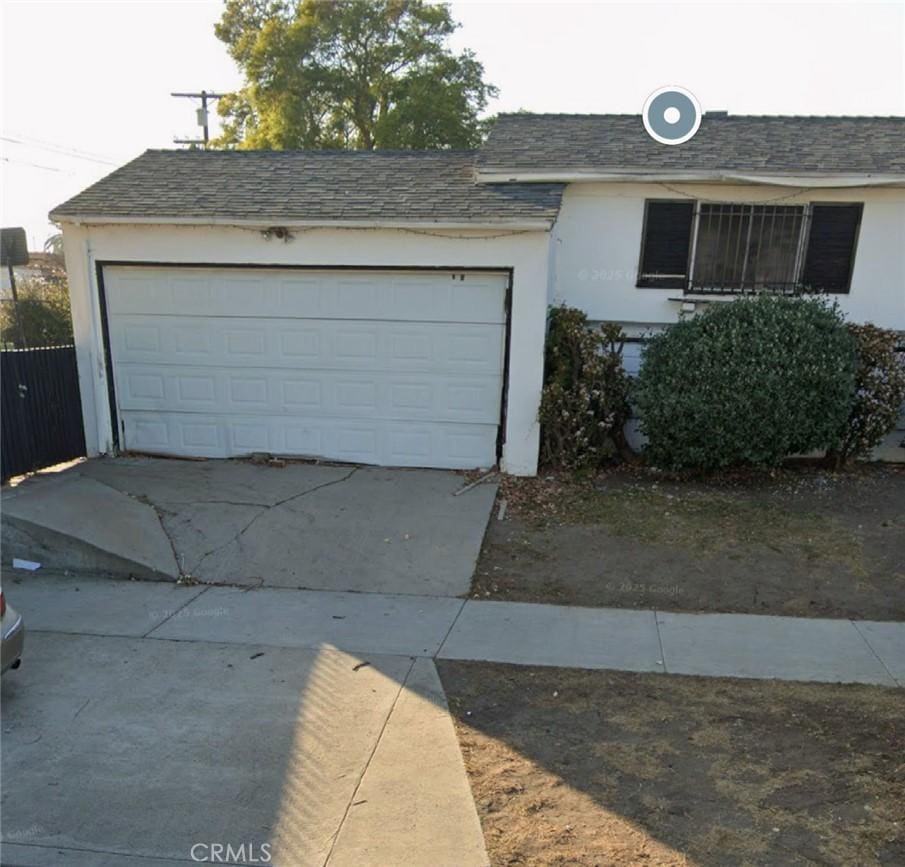 view of front of house featuring stucco siding, a shingled roof, and a garage