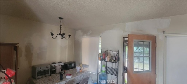 dining space with a textured ceiling, a chandelier, and a toaster