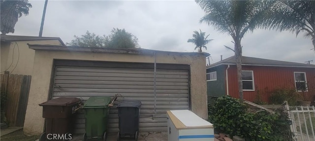 view of side of property featuring a garage, fence, and stucco siding