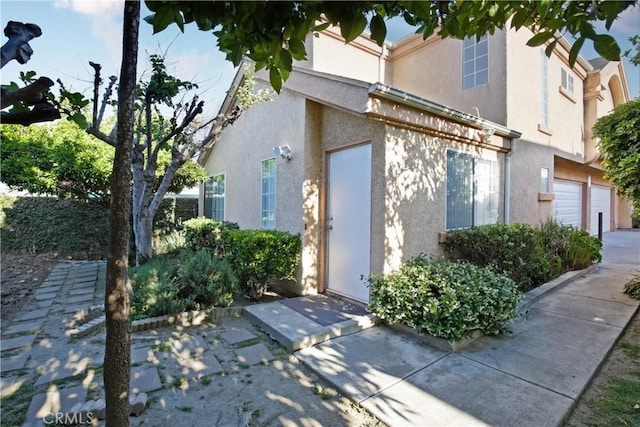 view of exterior entry with stucco siding, driveway, and an attached garage