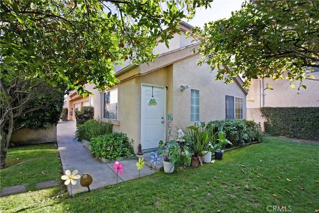 property entrance featuring stucco siding and a yard