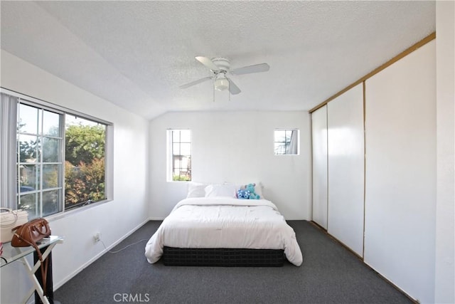 carpeted bedroom featuring lofted ceiling, a textured ceiling, a ceiling fan, and a closet