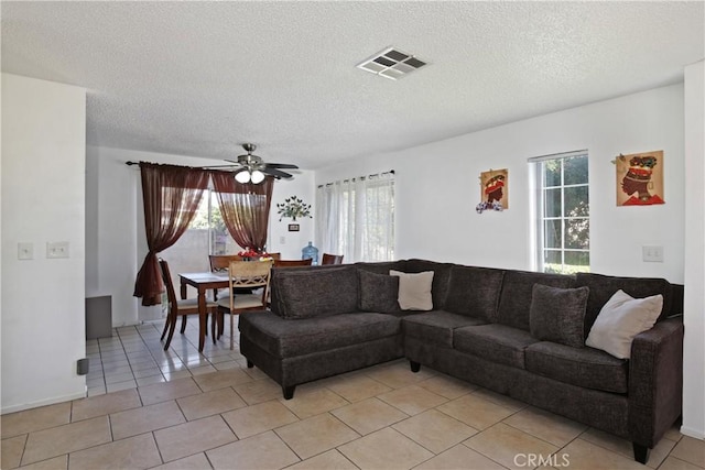 living area featuring light tile patterned floors, a textured ceiling, and ceiling fan