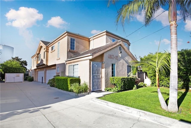 view of front of home featuring a garage, stucco siding, concrete driveway, a gate, and a front yard