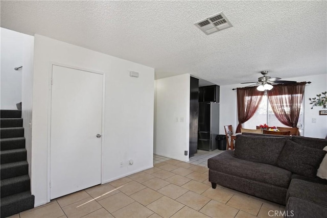 living area with stairway, light tile patterned flooring, a ceiling fan, and a textured ceiling