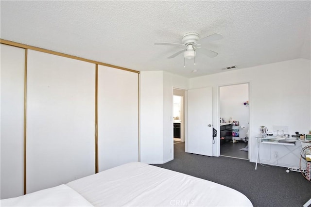 bedroom featuring dark carpet, a closet, a textured ceiling, and ceiling fan