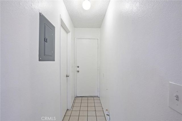 corridor with electric panel, light tile patterned floors, and a textured ceiling
