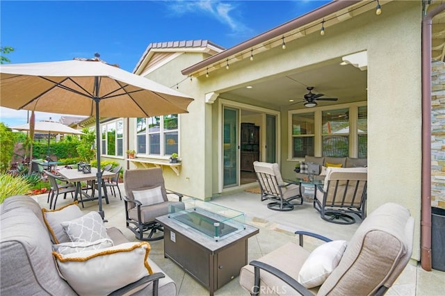view of patio featuring ceiling fan, outdoor dining area, and an outdoor living space with a fire pit