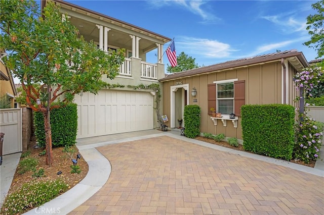 view of front of house featuring board and batten siding, an attached garage, decorative driveway, and a balcony