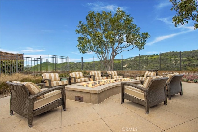 view of patio / terrace with fence, a mountain view, and an outdoor fire pit