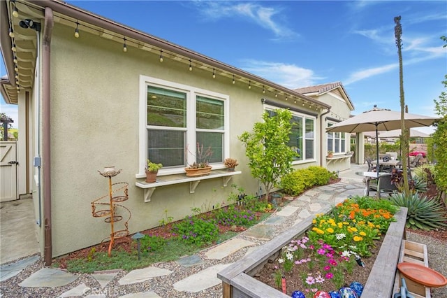 view of side of home featuring fence, a gate, a patio area, and stucco siding
