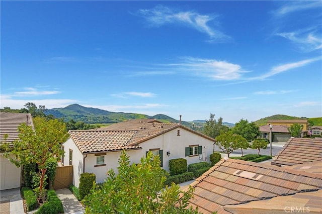 view of side of property featuring stucco siding, a gate, a mountain view, and a tile roof