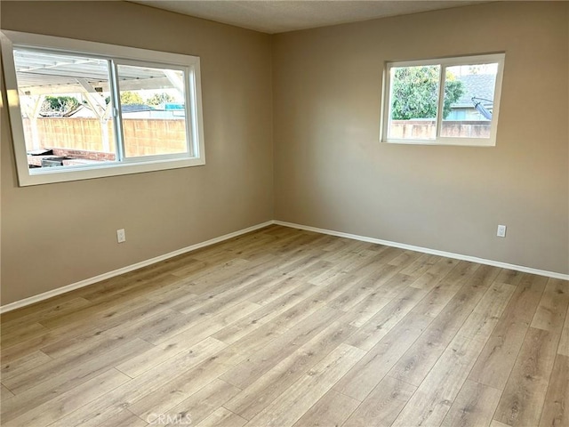 unfurnished room featuring baseboards and light wood-style floors