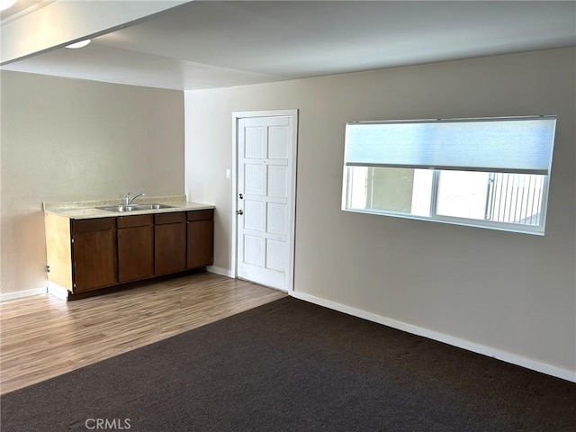 interior space featuring light countertops, baseboards, light colored carpet, and a sink