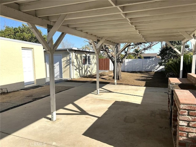 view of patio / terrace with fence, an outbuilding, and a storage shed