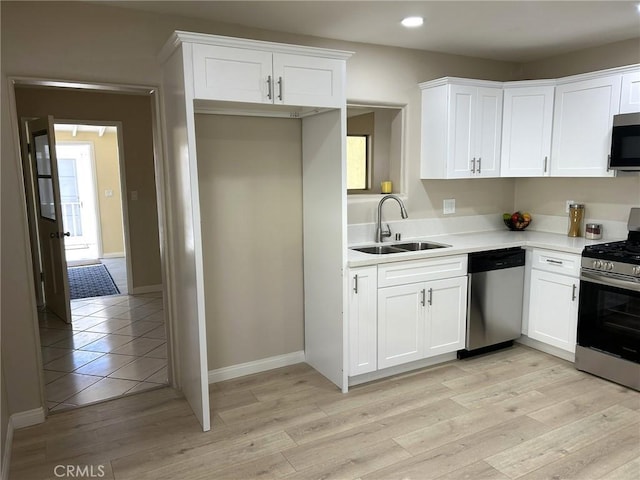 kitchen featuring recessed lighting, light countertops, white cabinetry, a sink, and appliances with stainless steel finishes