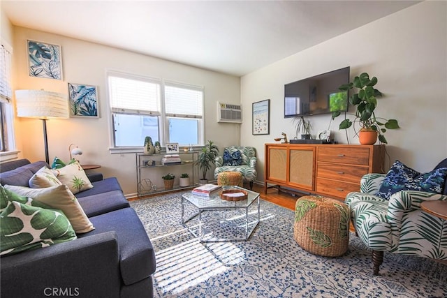 living room featuring baseboards, a wall unit AC, and wood finished floors
