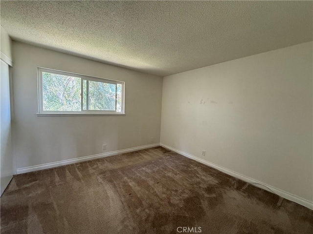 empty room featuring a textured ceiling, baseboards, and carpet