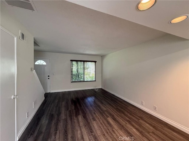 unfurnished living room with dark wood-style flooring, baseboards, and visible vents