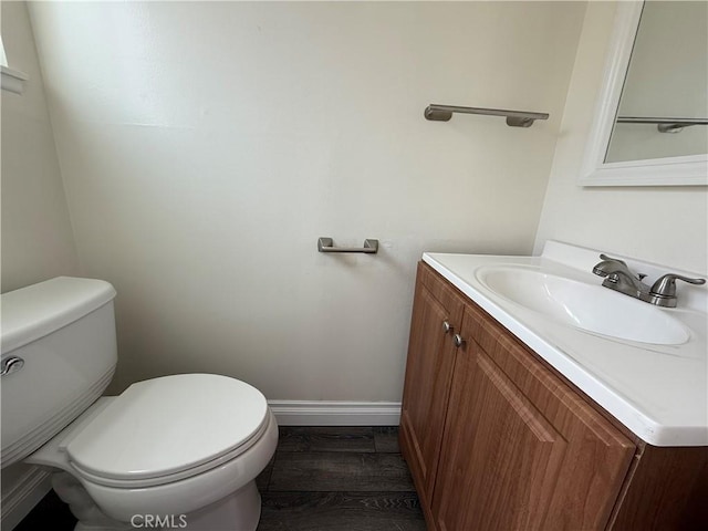 bathroom featuring toilet, baseboards, wood finished floors, and vanity