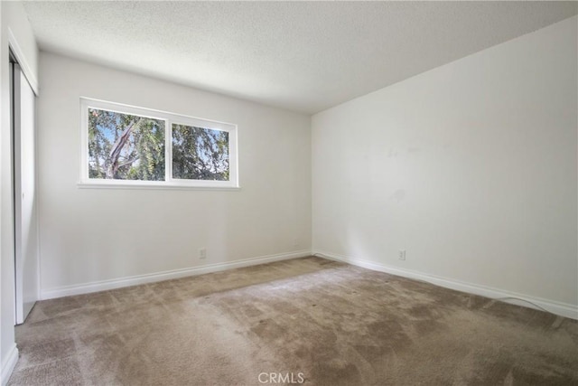 9867 Cornwall Dr, Huntington Beach, CA 92646 - empty room with carpet floors, baseboards, and a textured ceiling