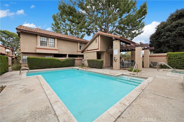 community pool with a patio and fence