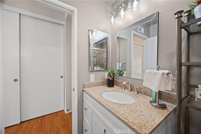 bathroom featuring vanity, a textured wall, wood finished floors, and visible vents