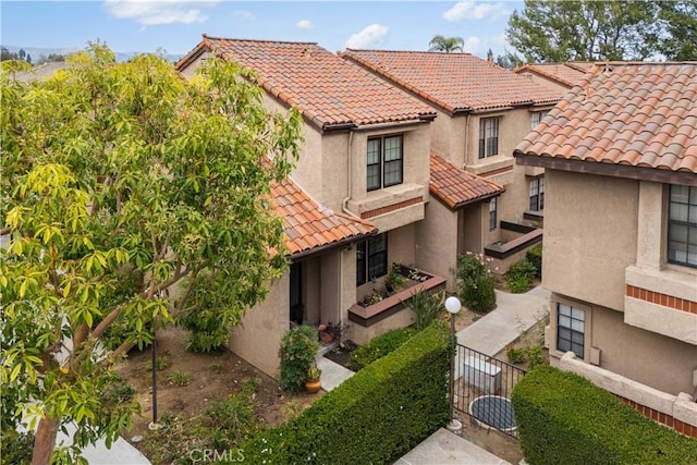 mediterranean / spanish house featuring a tiled roof, fence, and stucco siding