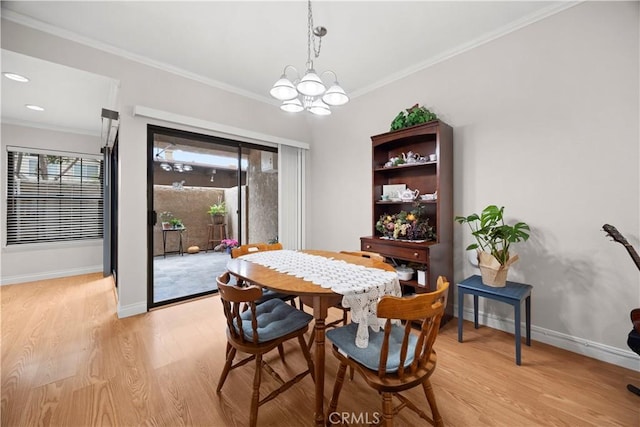 dining area featuring baseboards, light wood finished floors, crown molding, and an inviting chandelier