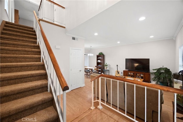 stairs featuring crown molding, visible vents, an inviting chandelier, wood finished floors, and recessed lighting