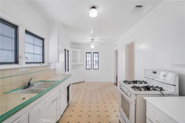 11584 Hallwood Dr, El Monte, CA 91732 - kitchen with white cabinets, a sink, tile counters, light floors, and white range with gas cooktop