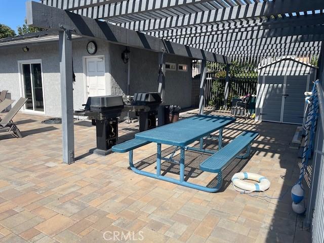view of patio / terrace with outdoor dining area, a storage shed, an outdoor structure, a pergola, and a grill
