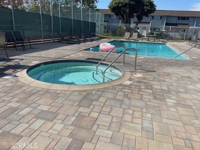 community pool with a patio, a community hot tub, and fence