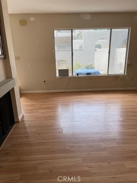 unfurnished living room with baseboards and wood finished floors