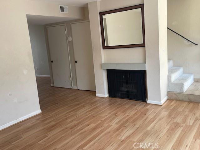 unfurnished living room with visible vents, light wood-style floors, and baseboards