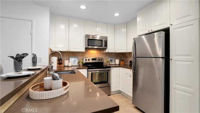 kitchen with backsplash, a sink, stainless steel appliances, recessed lighting, and white cabinetry