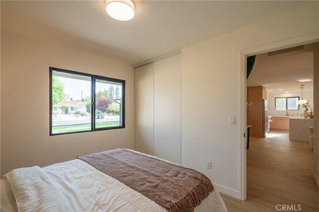 23919 Friar St, Woodland Hills, CA 91367 - bedroom featuring light wood-type flooring, a closet, freestanding refrigerator, and baseboards