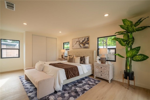 bedroom featuring baseboards, light wood-type flooring, recessed lighting, and a closet