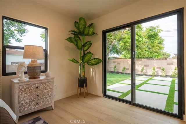 doorway to outside featuring healthy amount of natural light, wood finished floors, and baseboards