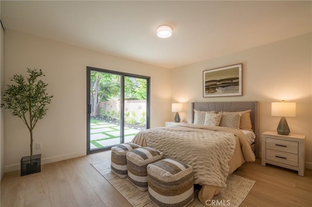 bedroom with access to outside, light wood finished floors, and baseboards