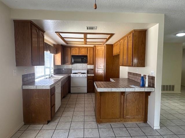 kitchen featuring range with gas cooktop, visible vents, black microwave, a peninsula, and light tile patterned flooring