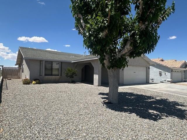ranch-style home featuring stucco siding, fence, driveway, and a garage